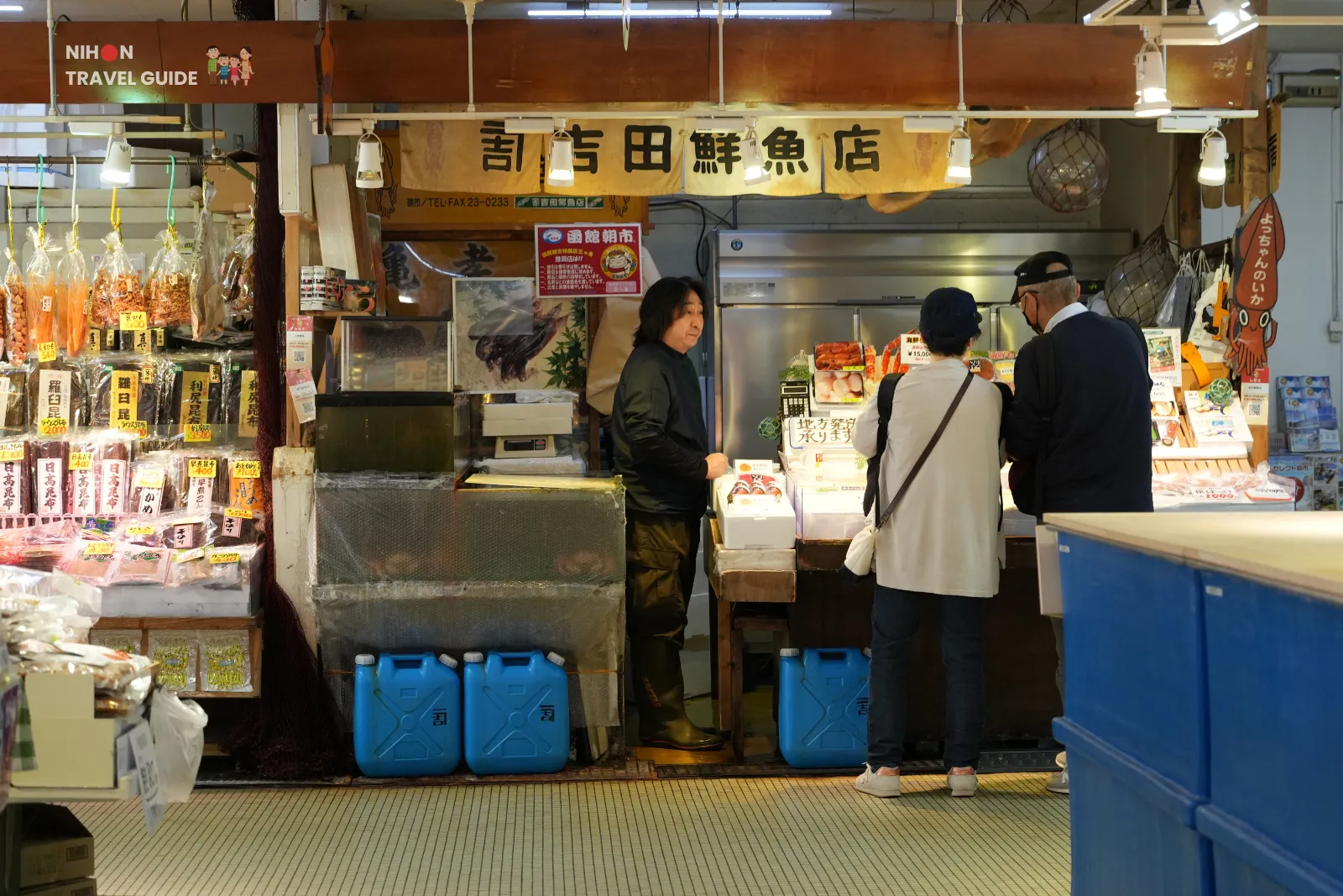Shoppers talking with a vendor at an indoor seafood stall in Hakodate Morning Market.