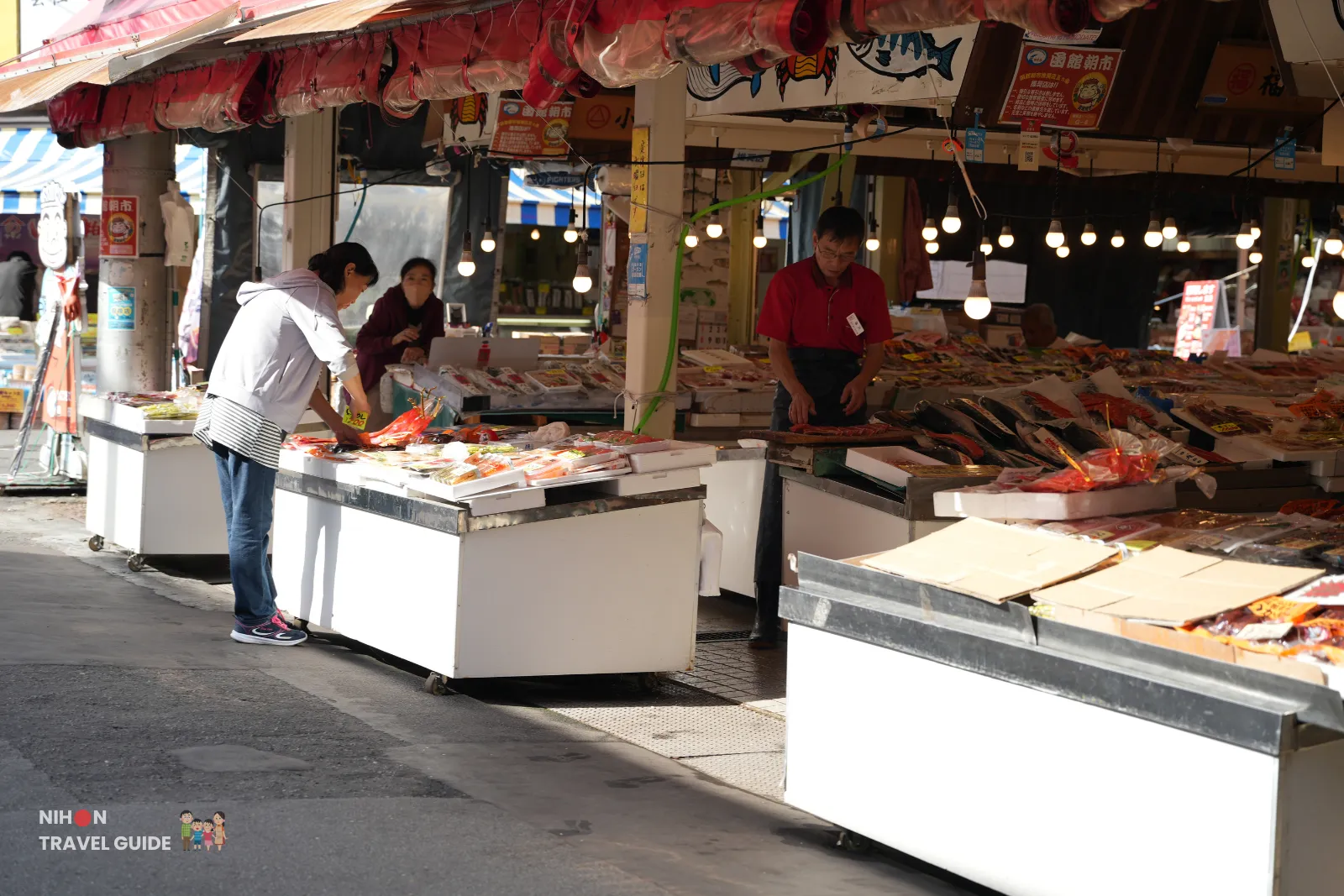 hakodate-morning-market-seafood-stalls Vendors arranging packaged seafood on chilled display tables at Hakodate Morning Market in Hokkaido, Japan.