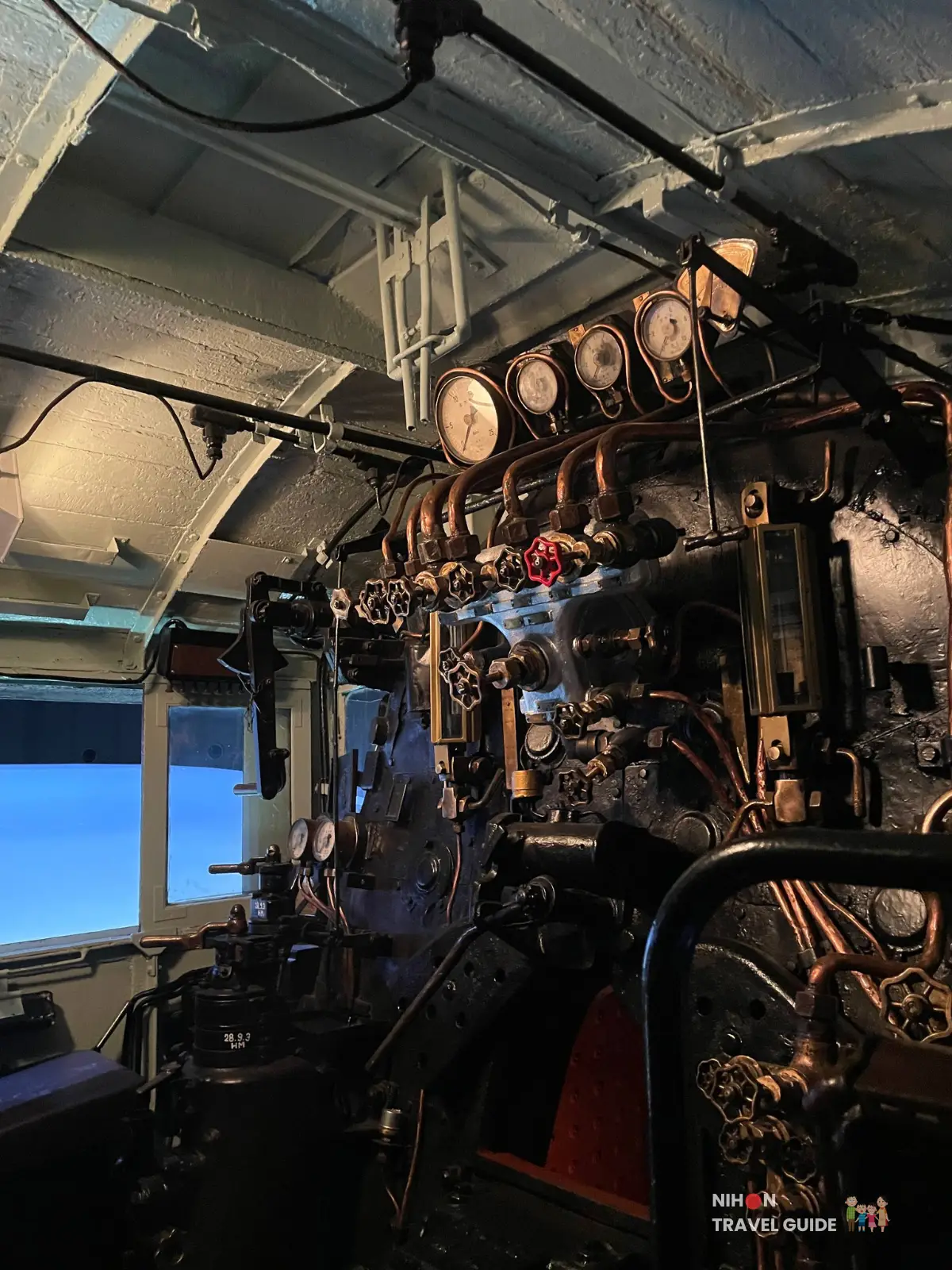 Steam locomotive cab at SCMaglev and Railway Park filled with gauges, valves, pipes, and levers used to operate the engine.