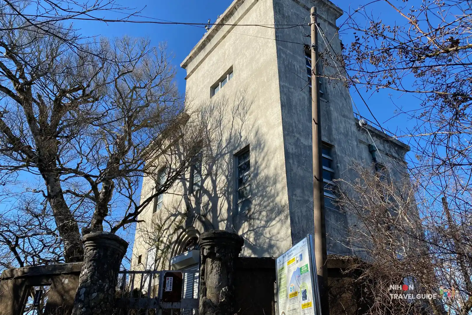 mt-tsukuba-nantaisan-meteorological-observation-station Concrete Meteorological Observation Station building near Nantaisan Peak on Mount Tsukuba, framed by leafless trees casting shadows on the walls beneath a clear blue sky.