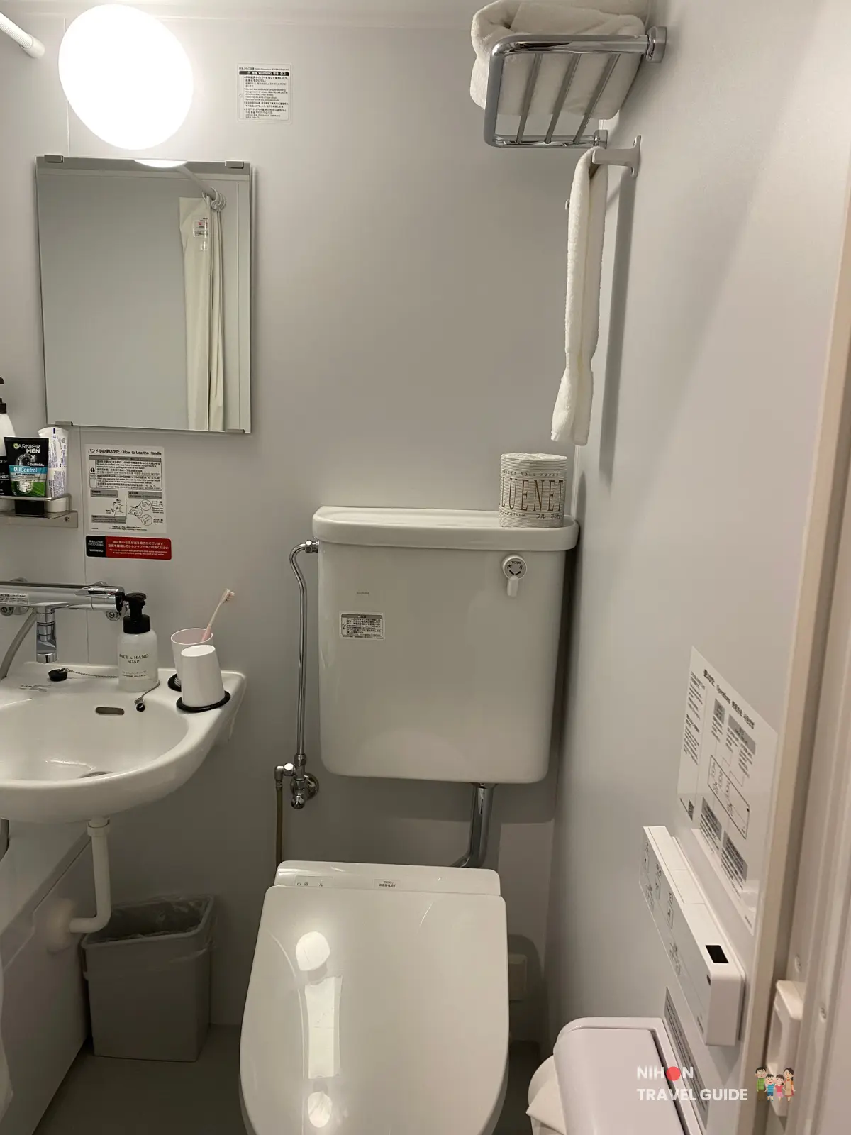 Compact bathroom at Hotel R9 The Yard Tsukuba with Japanese toilet, small sink, mirror, and towel rack.