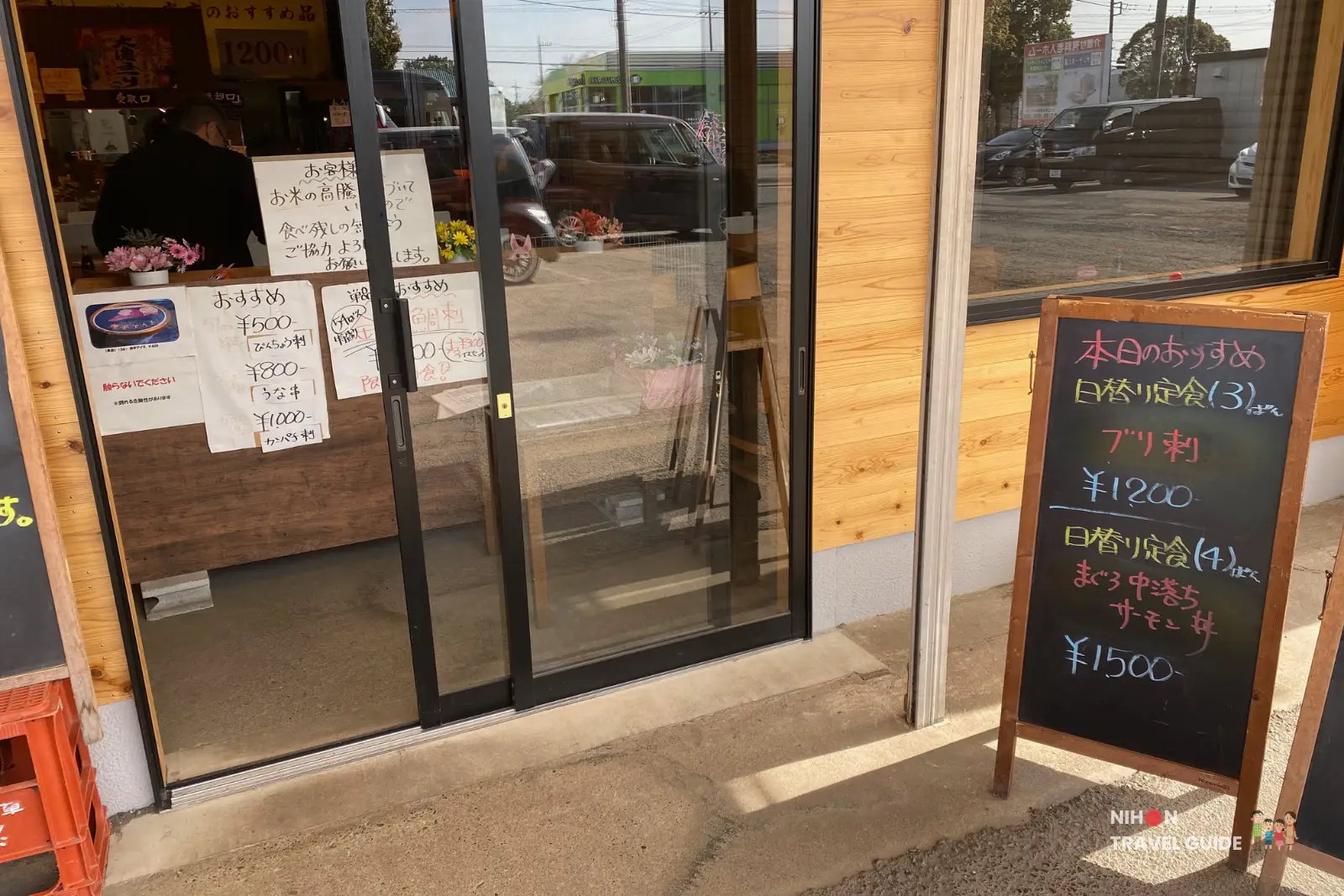 Glass door entrance to Tsuchiura Fish Market canteen with polite Japanese notices, daily recommendation signs, and locals inside.