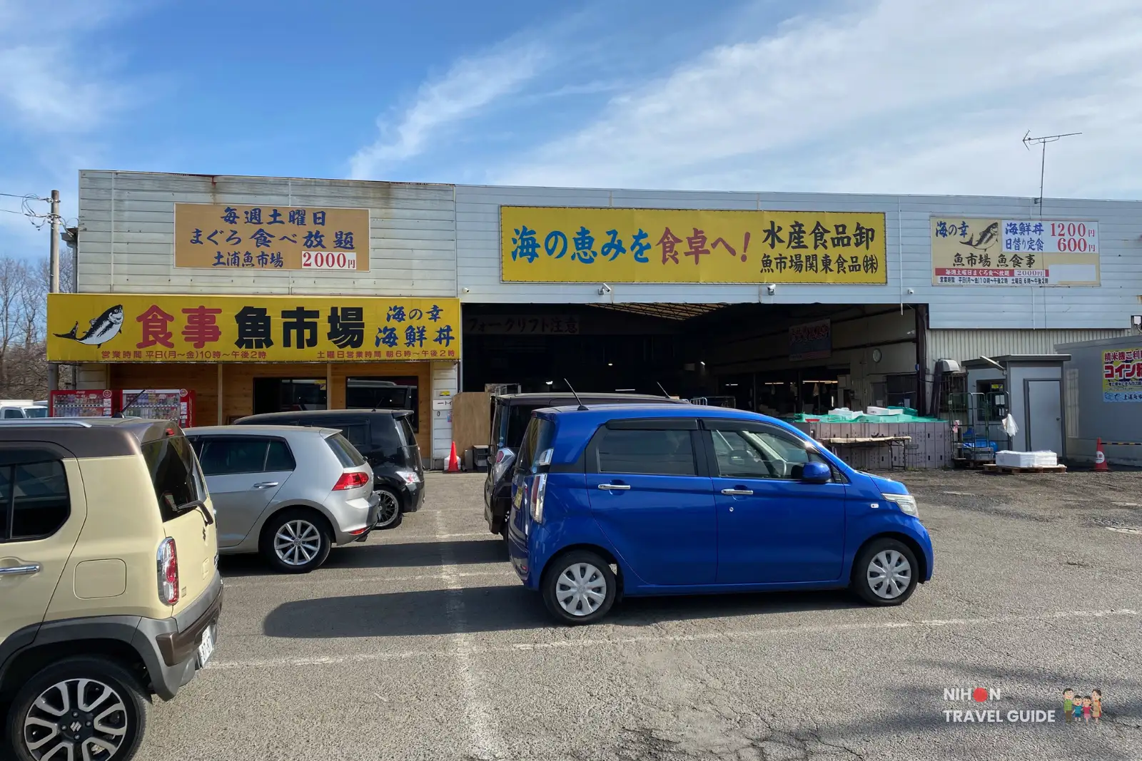 Front exterior of Tsuchiura Fish Market (土浦魚市場) with large banners advertising Saturday maguro all-you-can-eat for ¥2000, parking lot, and warehouse entrance, February 2026