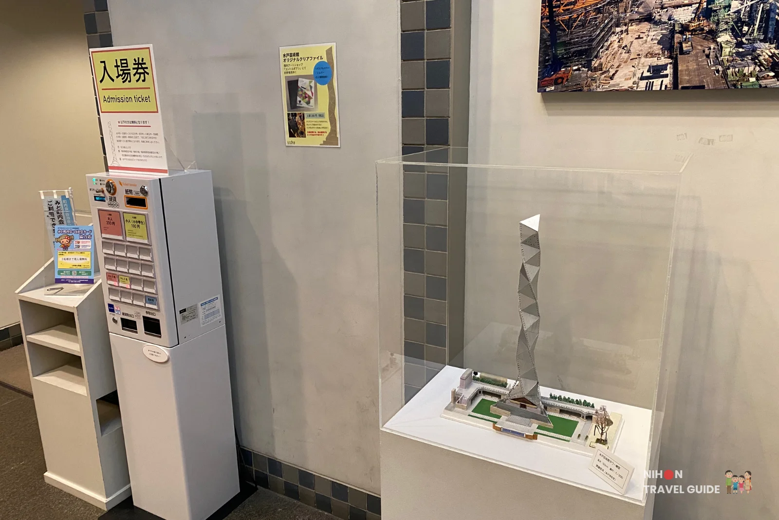 Architectural scale model of Art Tower Mito displayed in a glass case in the tower's lobby, next to the admission ticket vending machine showing prices of ¥200 for adults and ¥100 for children, Mito City, Ibaraki, Japan