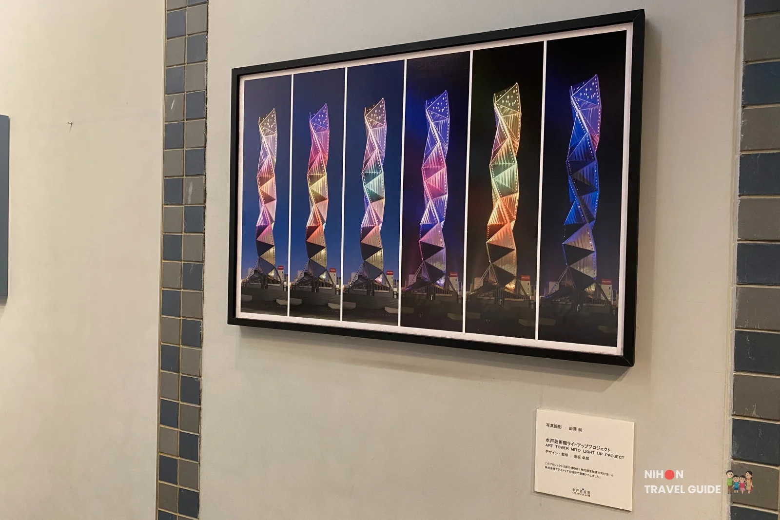 Framed display showing the Art Tower Mito Light Up Project, featuring six panels of the tower illuminated in different colours including pink, blue, purple, and gold at night, designed by Takao Inoue, Mito City, Ibaraki, Japan