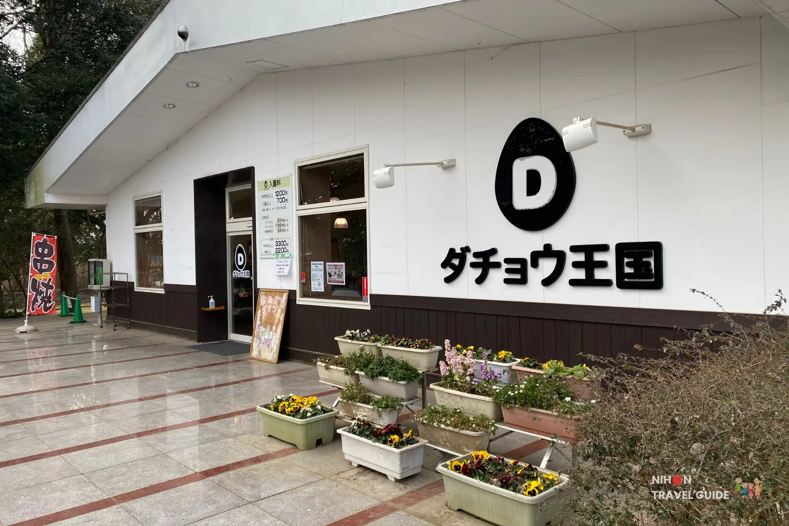 ishioka-ostrich-farm-main-building-entrance Front of Ishioka Ostrich Farm main building with large logo, flower planters and admission sign by the entrance.