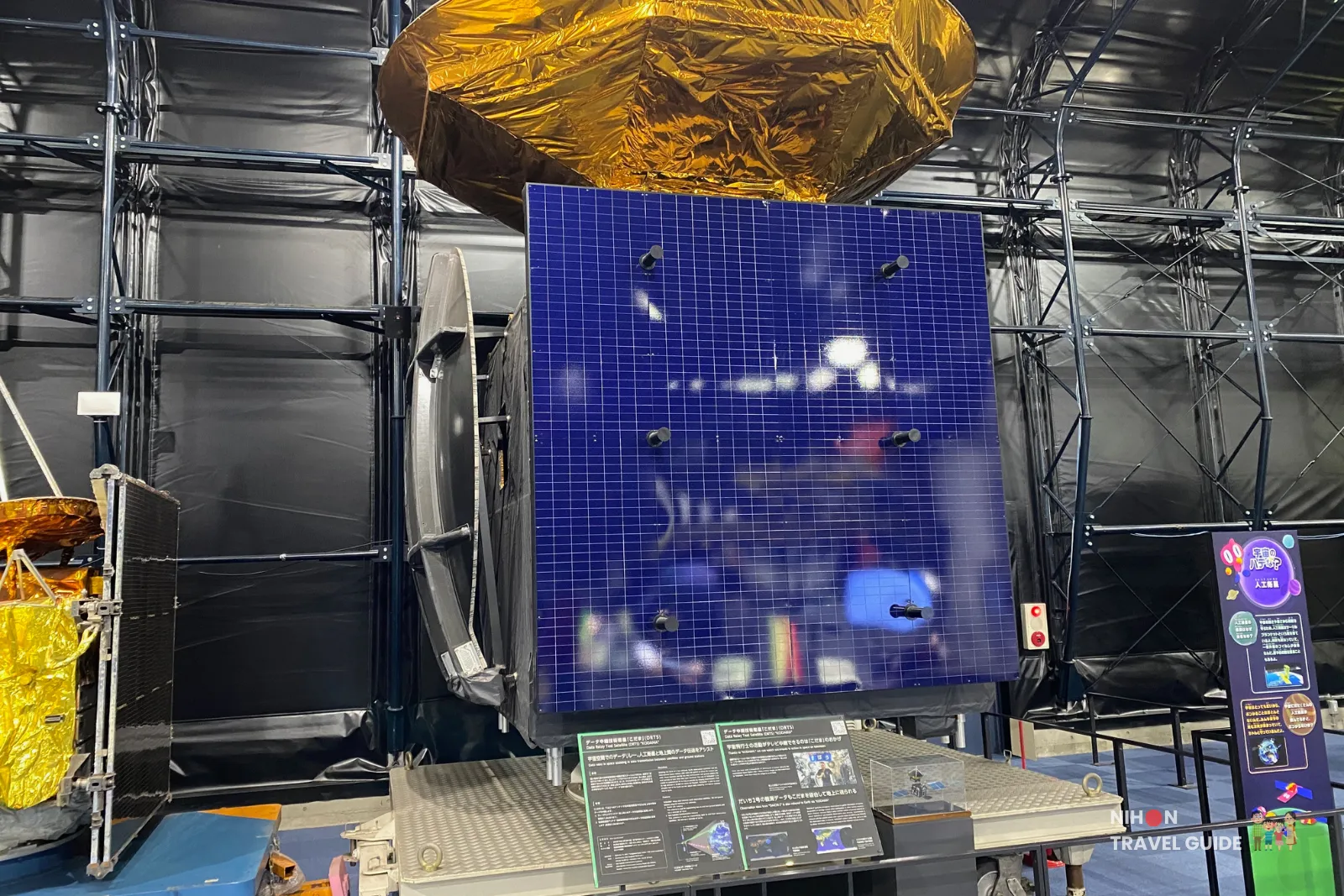 JAXA KODAMA (DRTS) satellite engineering model exhibited at Tsukuba Space Center Space Dome, showing large blue solar panel and gold thermal blanket.