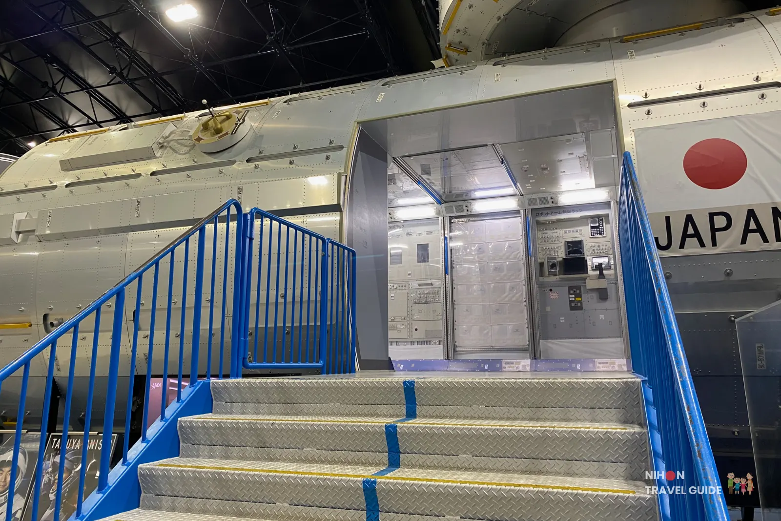Close-up view of the entrance stairs leading into the JAXA Kibō module mock-up, showing the open hatch and control panels just inside.