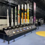 Lineup of scale models of Japanese launch vehicles, from early rockets to modern H-II and H3 designs, on display inside the Space Dome at JAXA Tsukuba Space Center.