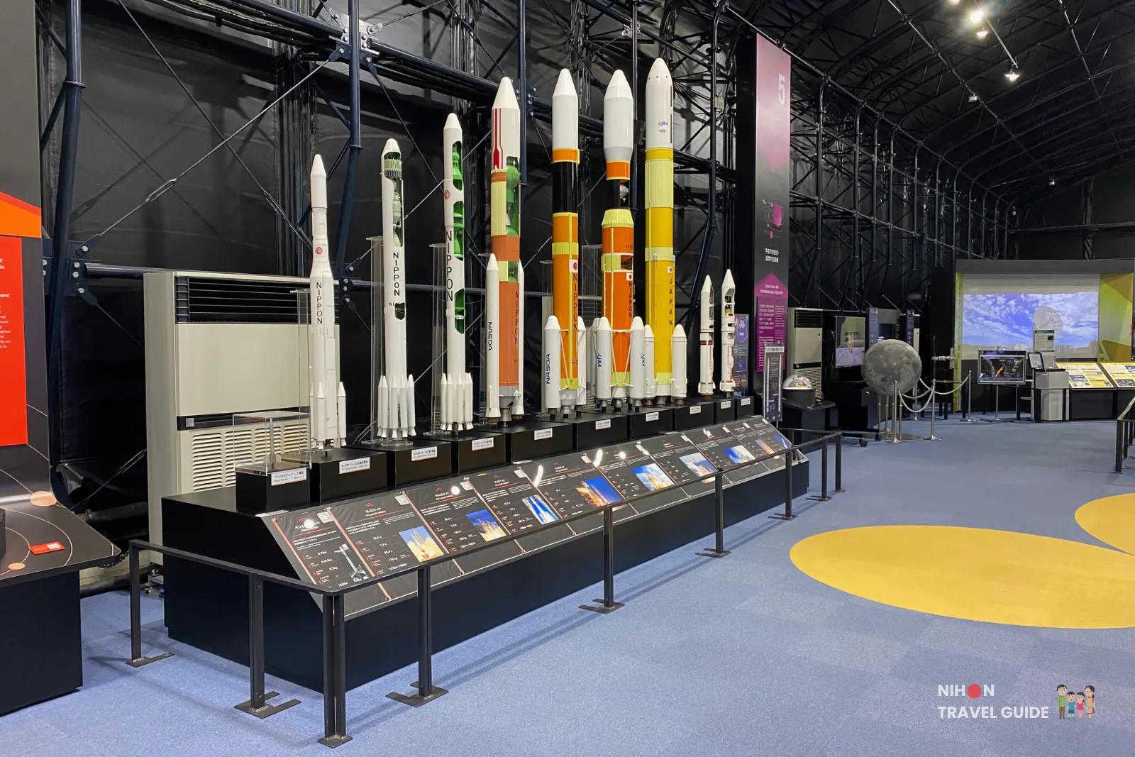 Lineup of scale models of Japanese launch vehicles, from early rockets to modern H-II and H3 designs, on display inside the Space Dome at JAXA Tsukuba Space Center.