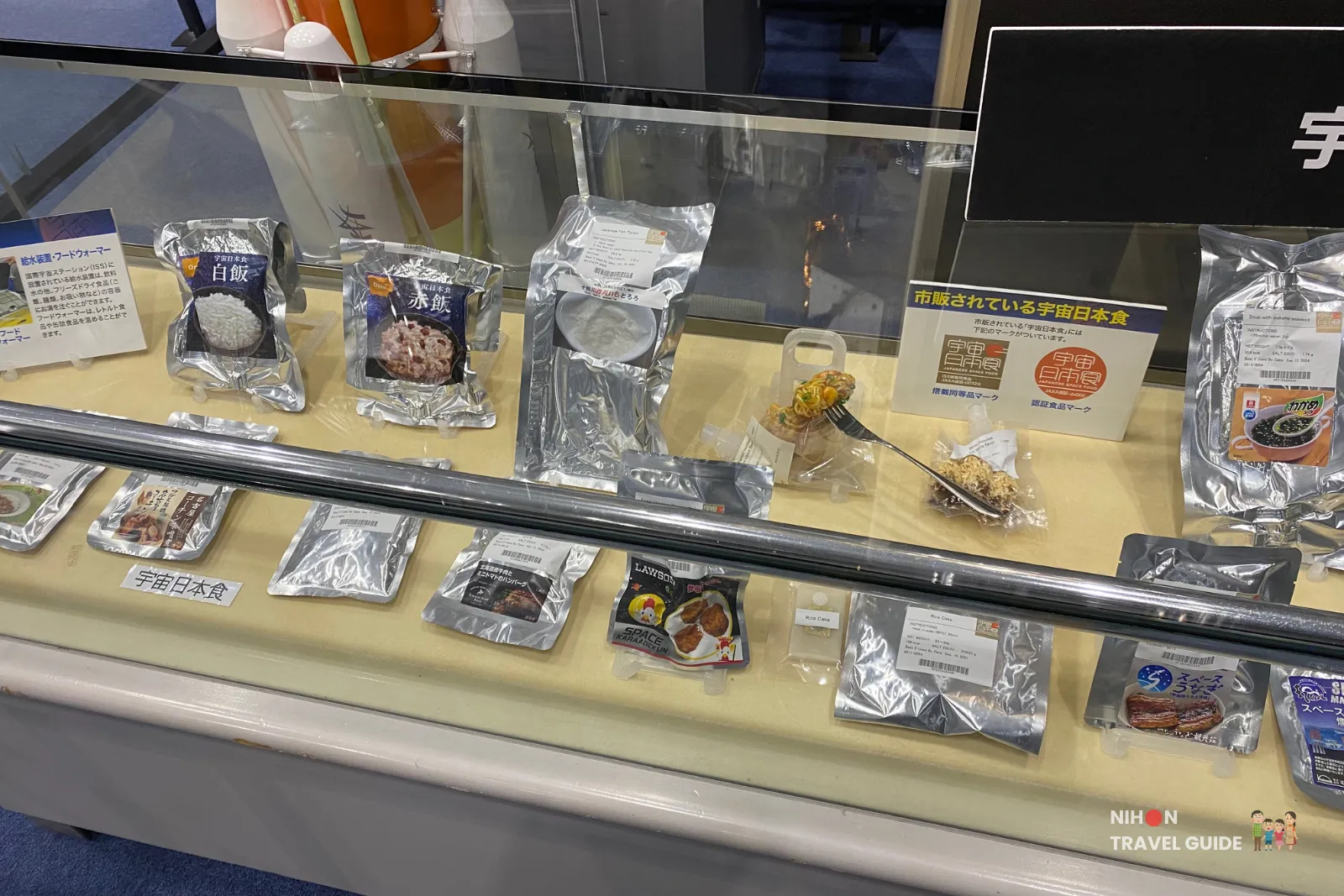 Exhibit panel about how astronauts eat in space with assorted Japanese space food samples displayed below in the Space Dome at JAXA Tsukuba Space Center.