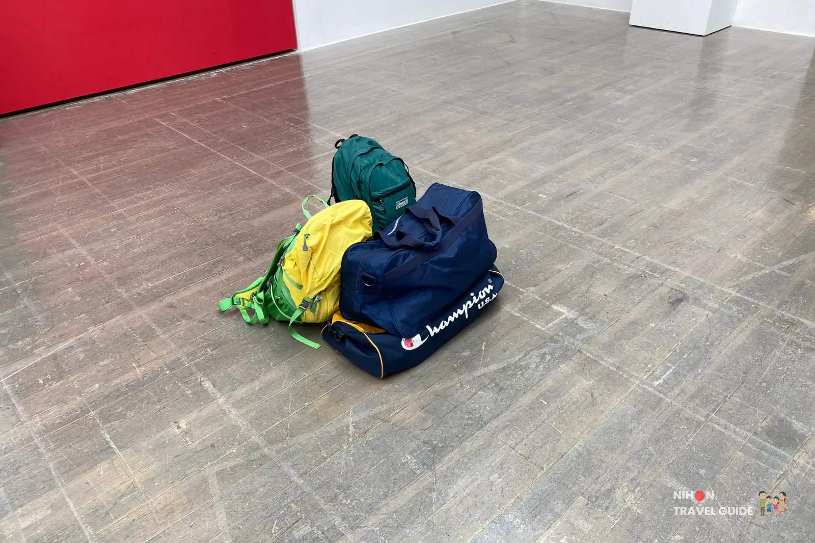 Pile of colorful backpacks and duffel bags on the gallery floor as part of Takehiro Iikawa’s “Decorator Crab — Make Space, Use Space” exhibition.