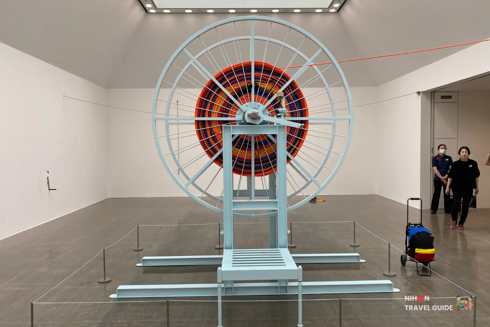 Massive light-blue wheel sculpture wound with colorful ropes in the Takehiro Iikawa "Gathering Matters and Mediations" exhibition at Art Tower Mito.