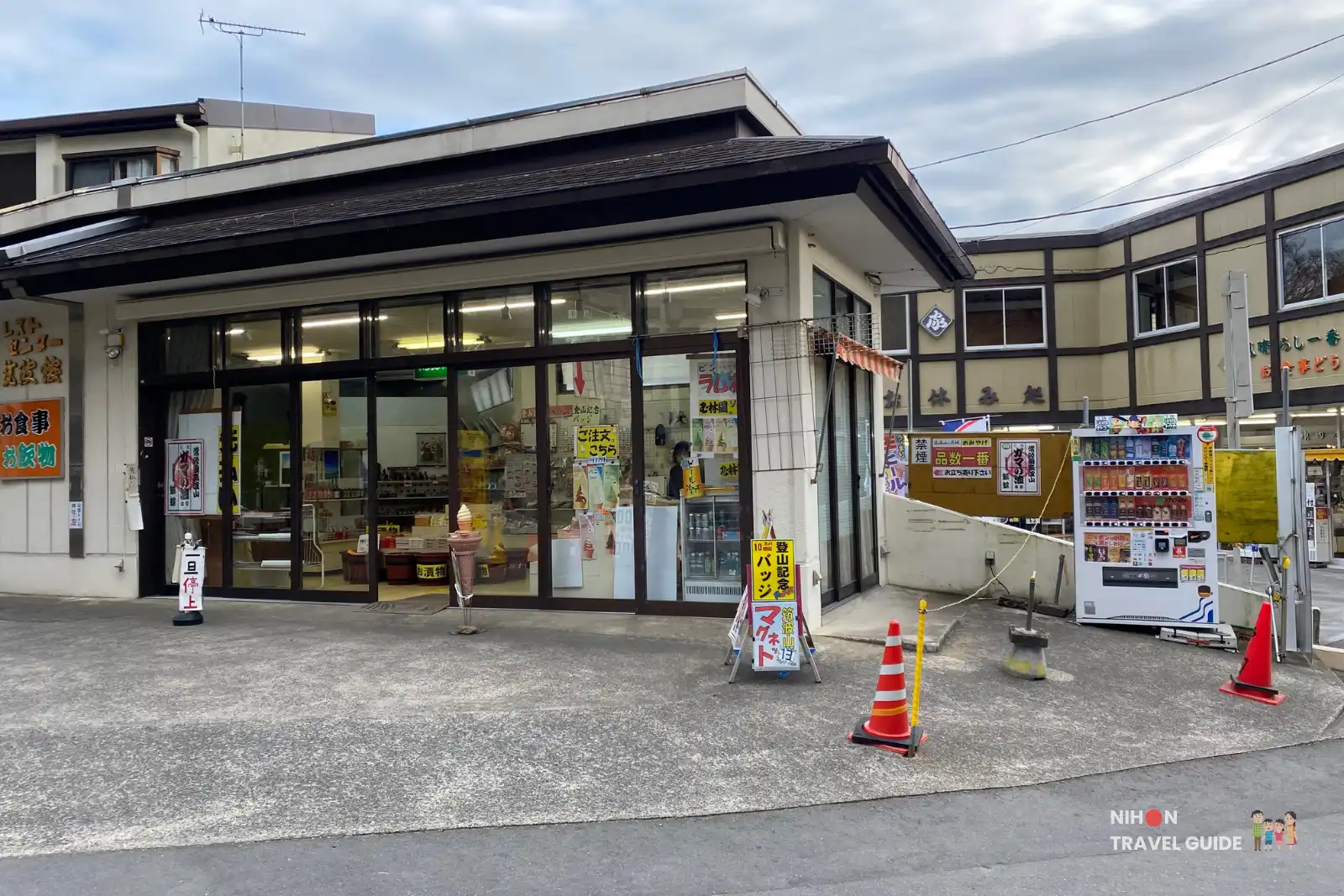 Entrance to the restaurant section of Kandaya near Tsukubasan Shrine, with large glass windows, food posters, and an ice cream cone statue outside.
