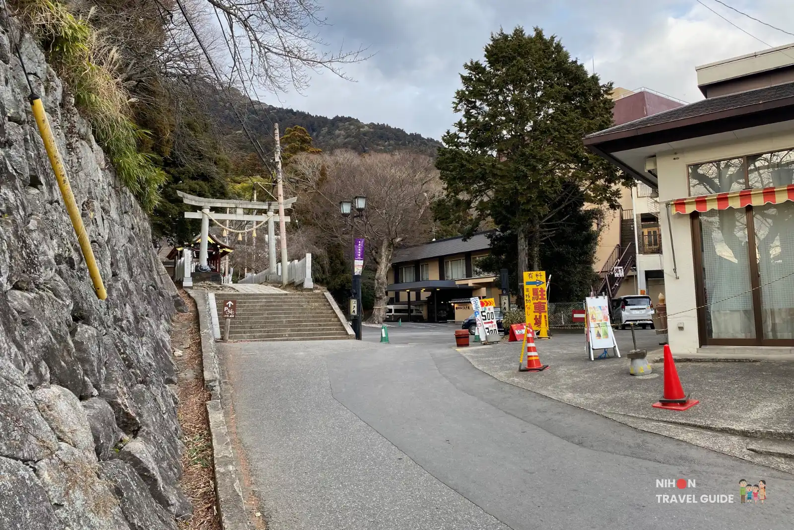 Road and stone steps leading up to the second torii gate on the approach to Tsukubasan Shrine, with small inns and shops on the right.