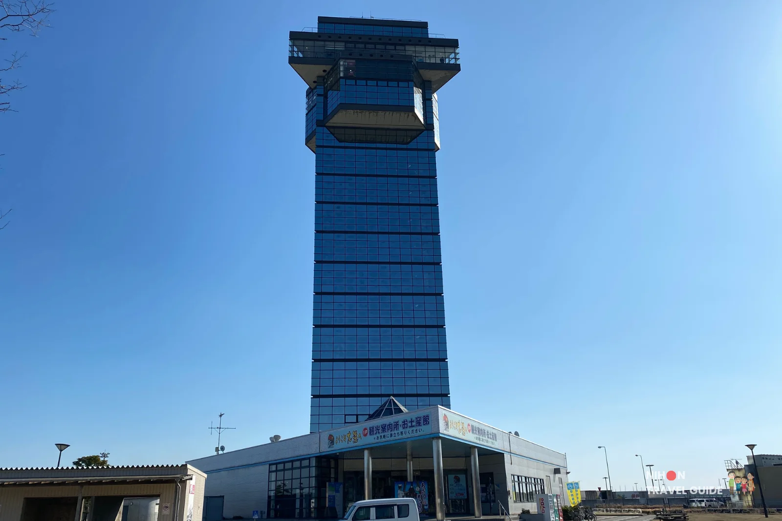 Oarai Marine Tower, a tall blue-glass observation tower in Oarai, Japan, viewed from the ground against a clear blue sky.
