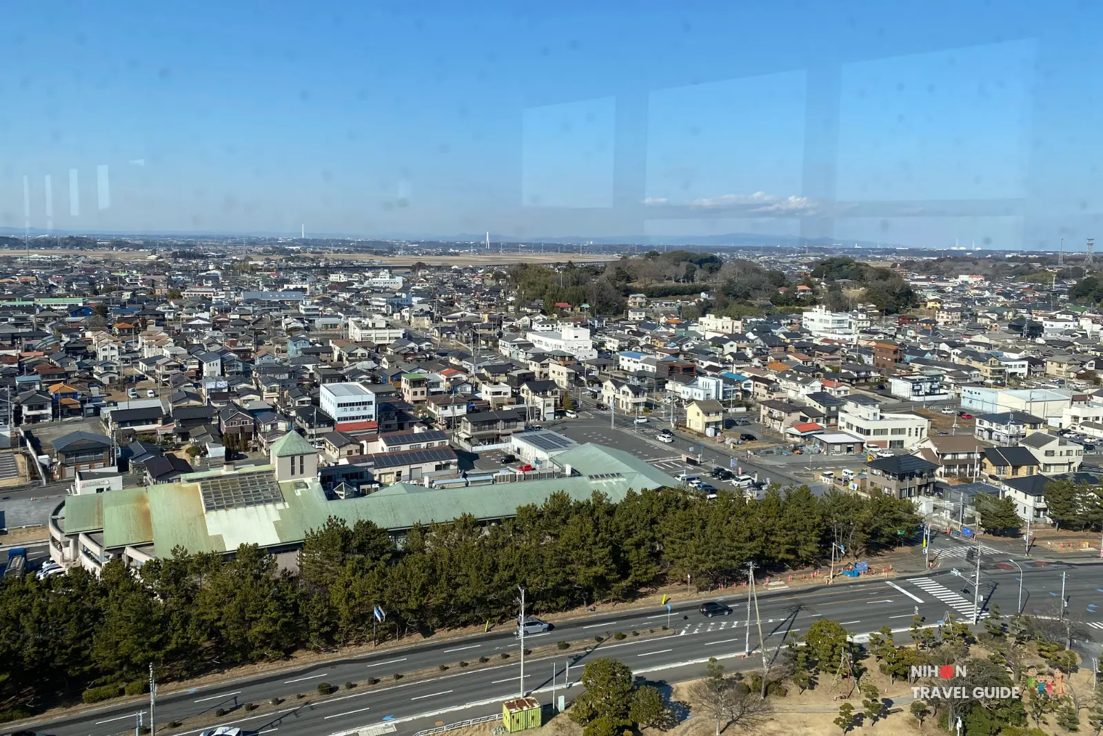 Panoramic southwest-facing view from Oarai Marine Tower observation deck displaying the full spread of Oarai town, major roads, residential neighborhoods, and distant mountain ranges including Tsukuba and Kaba on the horizon, Ibaraki, Japan