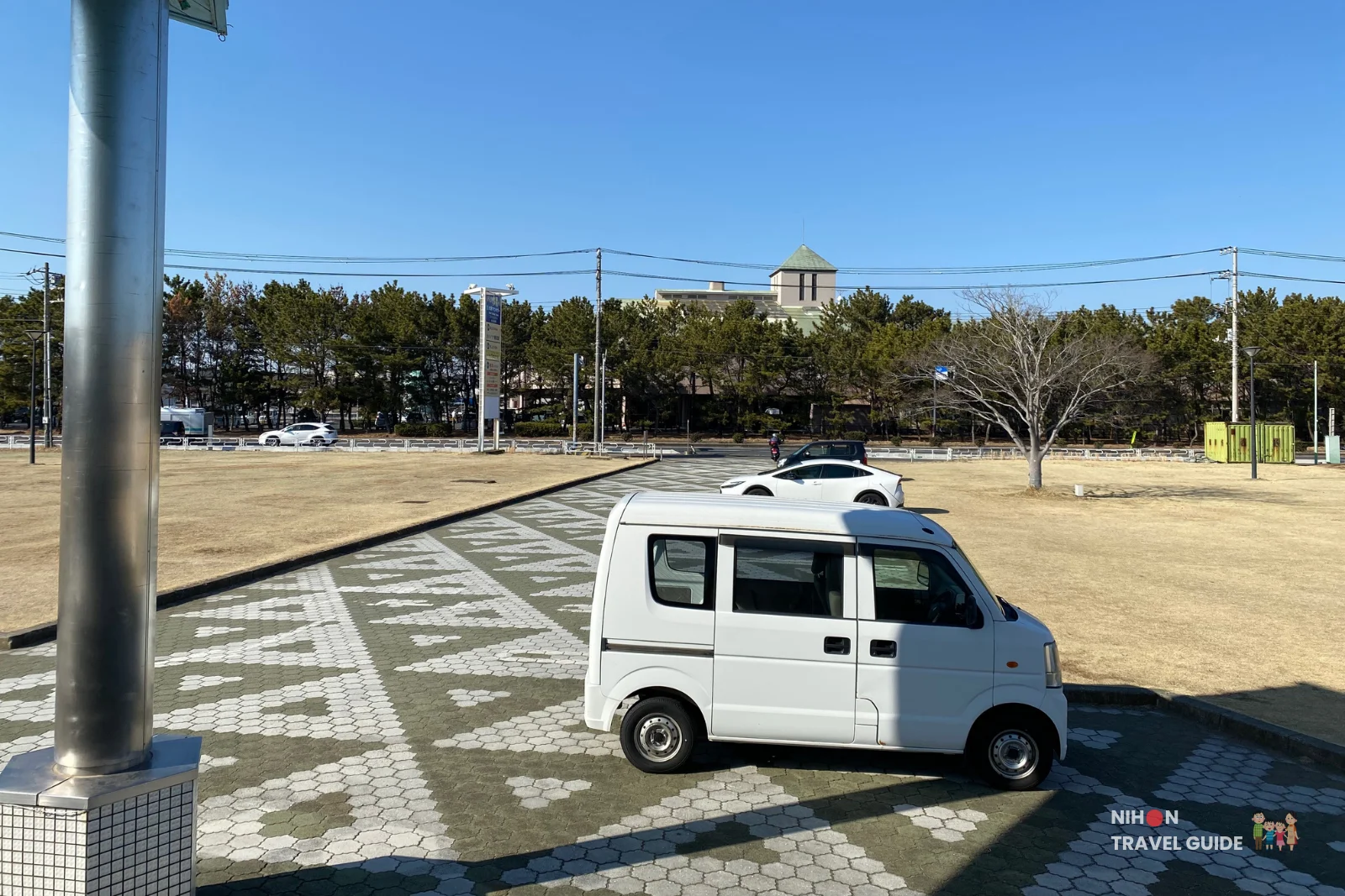 oarai-marine-tower-parking-area Parking area outside Oarai Marine Tower on a clear sunny day, with a white kei van parked on patterned paving stones and the tower visible in the background, Ibaraki Prefecture, Japan