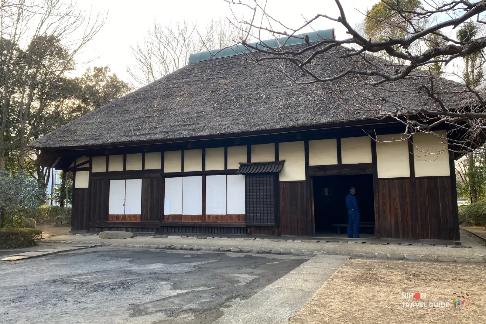 Traditional Japanese thatched-roof minka (farmhouse) at Sakura Minka-en near Tsukuba Expo Center. This historic wooden building features classic dark wood and white walls under a thick thatch roof.