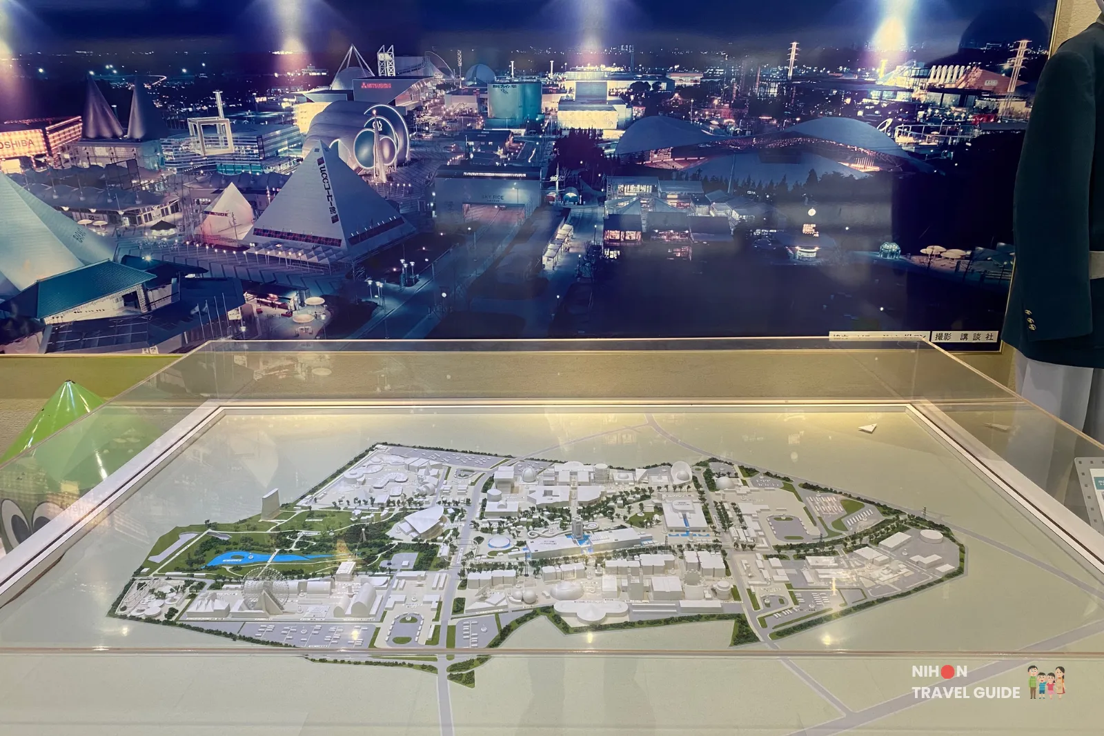 Large illuminated model of the 1985 Tsukuba Expo grounds displayed under a dramatic night-time aerial photograph of the entire site in the Expo '85 Memorial.