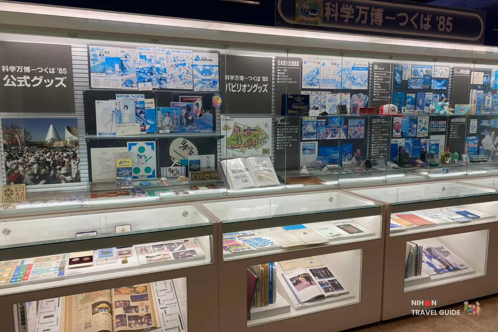Glass display cases in the Expo '85 Memorial featuring official goods, pamphlets, maps, posters, and souvenirs from the various pavilions of the 1985 Tsukuba Expo.