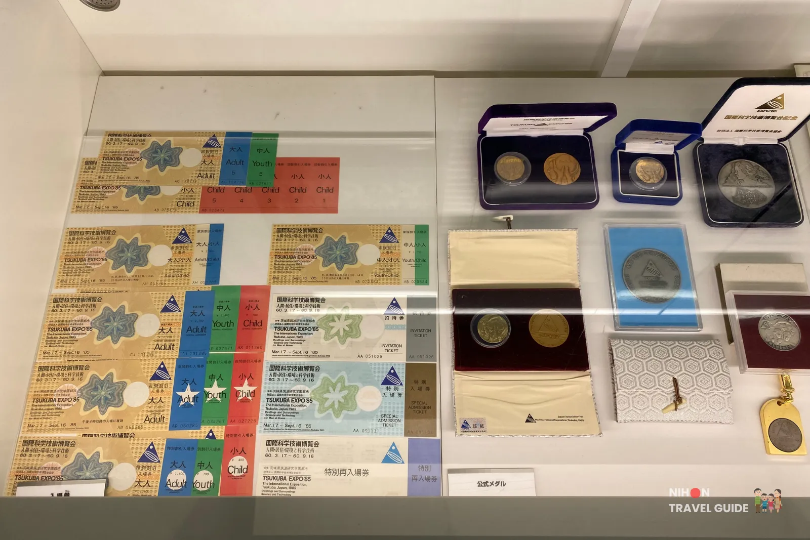 Display case in the Tsukuba Expo '85 Memorial showing original admission tickets in multiple colors and commemorative medals from the 1985 International Science and Technology Exposition.