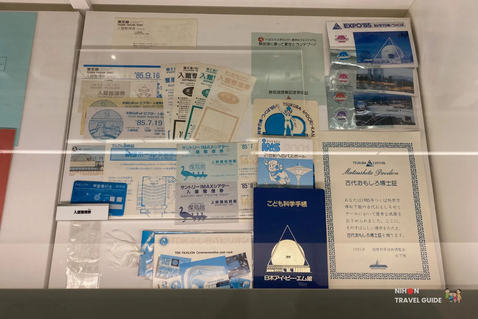 Detailed view of original admission tickets, pavilion entrance passes, and commemorative items from the 1985 Tsukuba Expo displayed in the memorial exhibition.