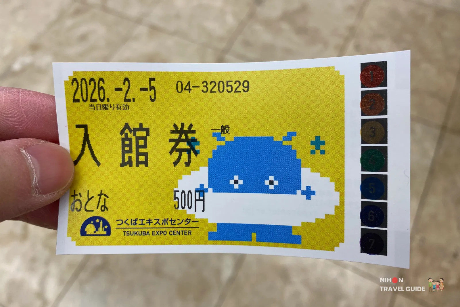 Tsukuba Expo Center admission ticket: yellow card with 500円, event date 2026-2-5, and a blue pixel mascot on the right.