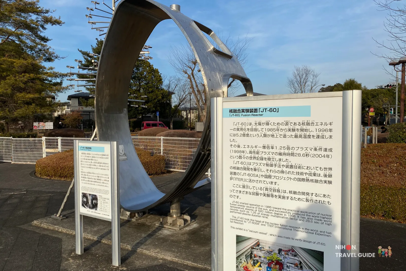 Large stainless steel JT-60 fusion reactor model (vacuum vessel) displayed outdoors at Tsukuba Expo Center, with detailed explanatory panels about nuclear fusion research.
