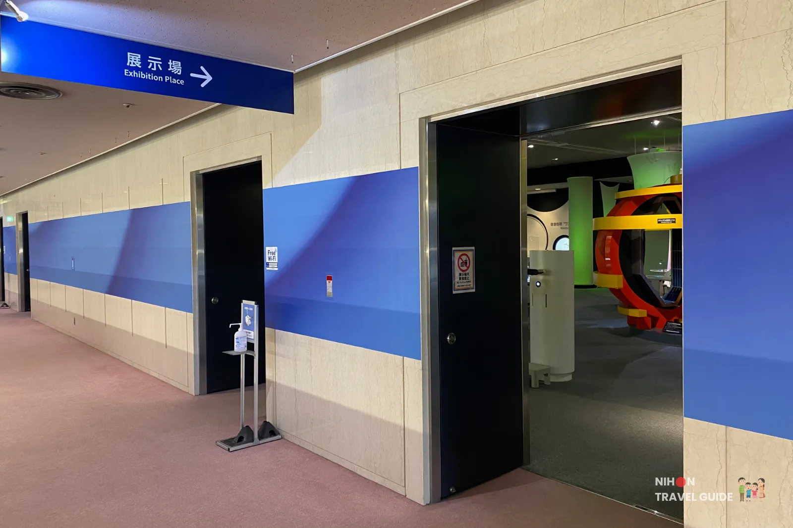 Entrance to the second floor exhibition halls at Tsukuba Expo Center. A clear blue overhead sign points to the “Exhibition Place” (展示場), leading visitors to the advanced science zones including space, deep sea, and nanotechnology exhibits.