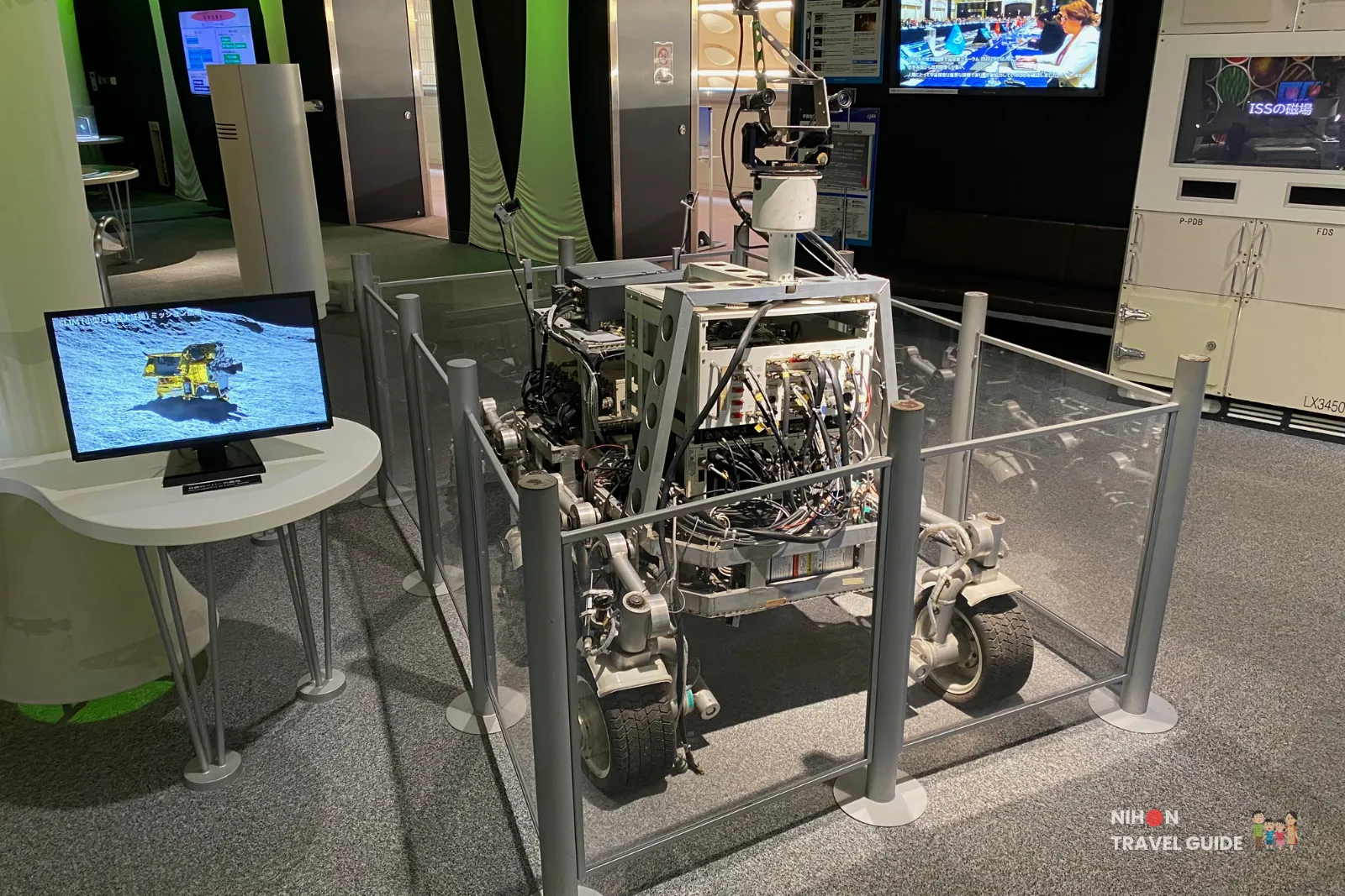 Detailed model or replica of a lunar rover / planetary exploration robot on the second floor. A monitor shows related footage, with the International Space Station module visible in the background.
