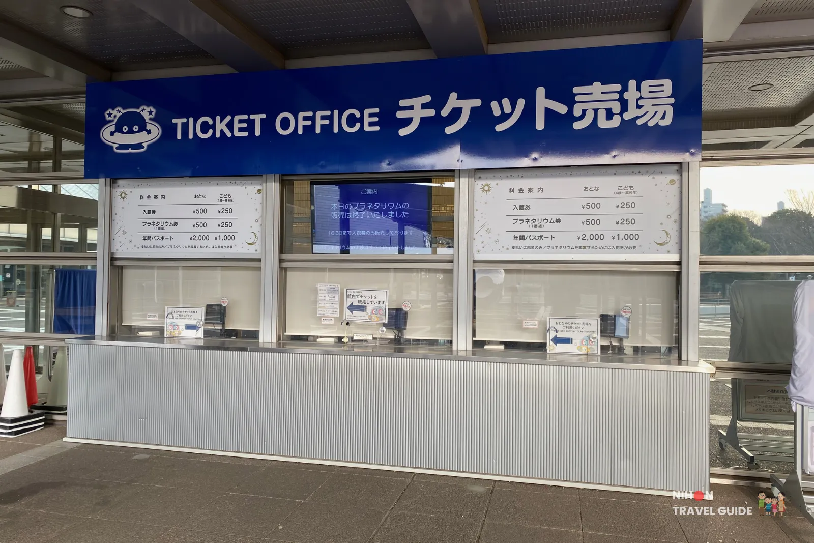 Ticket office at the entrance of Tsukuba Expo Center with clear pricing signs for general admission (¥500 adults / ¥250 children) and planetarium tickets.