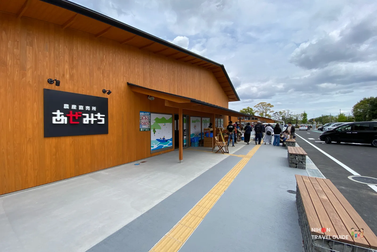 Exterior of Azemichi (あぜみち) agricultural direct sales shop at Mito Kobun Terrace, with visitors and the parking area visible.