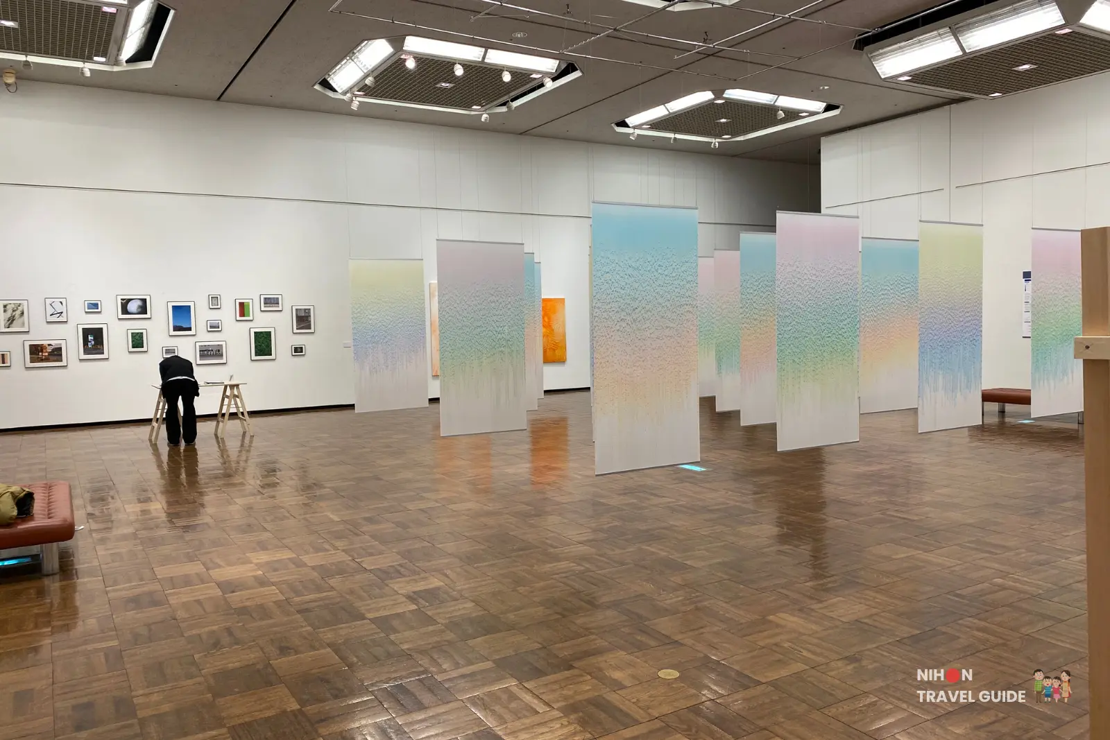 Main gallery of Tsukuba Museum of Art showing the Flow hanging gradient panels by Saya Takama and the photography series My room \ My story on the left wall