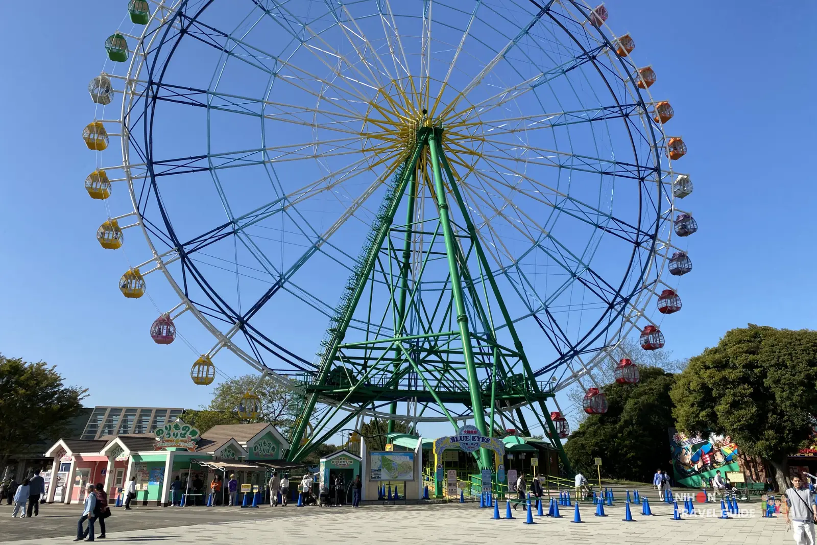 The iconic Blue Eyes Ferris Wheel (100m tall) in the Pleasure Garden at Hitachi Seaside Park, viewed from below on a clear blue sky day.
