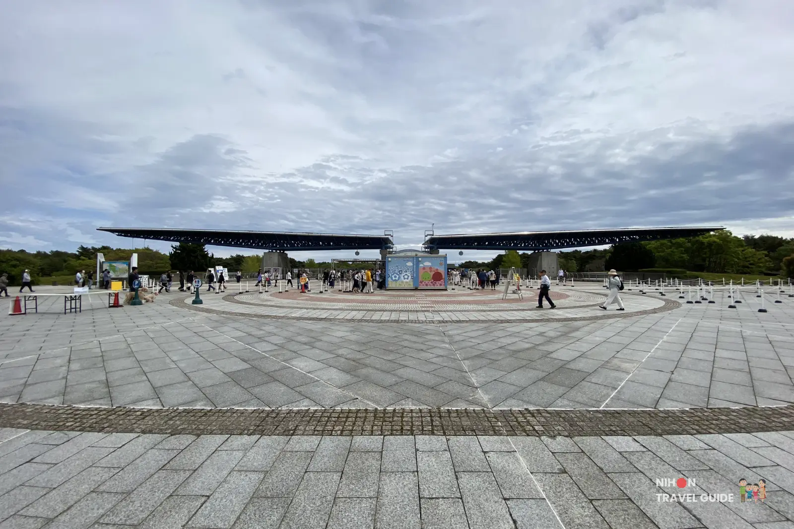 Main entrance plaza at Hitachi Seaside Park with the large iconic gate structure and visitors walking around.