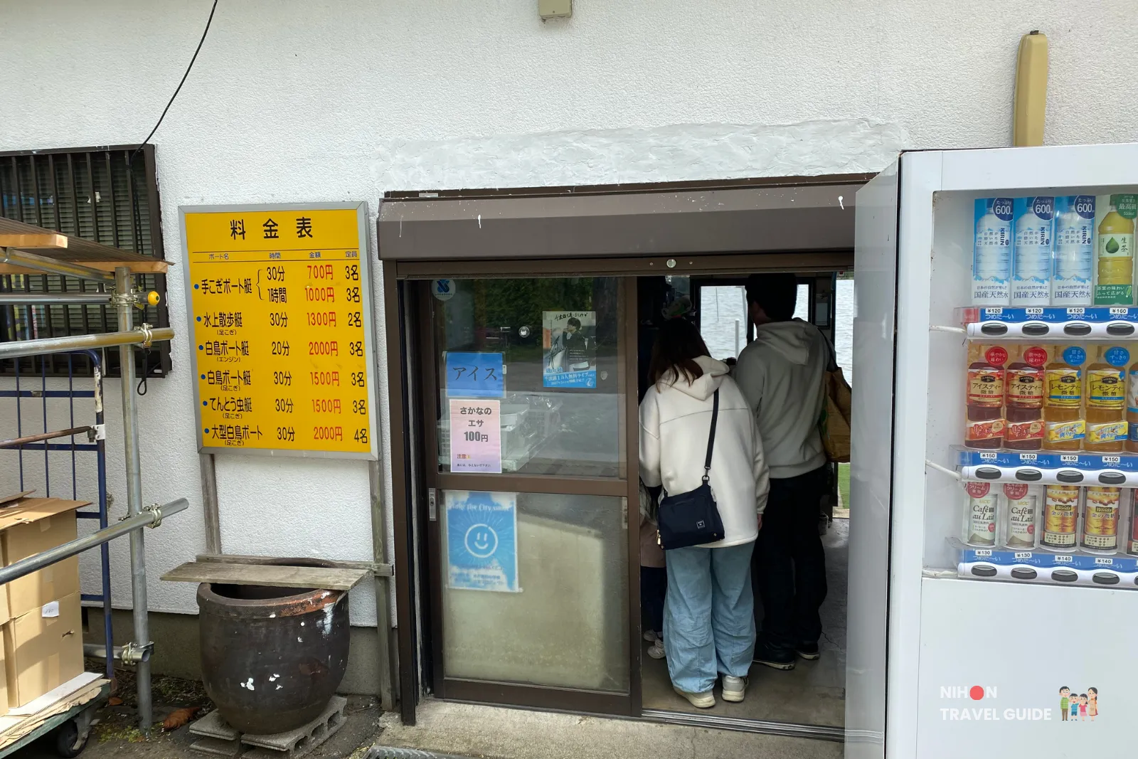Entrance of Ishikawa Boat Rental Shop (石川貸ボート店) at Lake Senba in Mito, with visitors at the counter, price list for rowboats and swan boats, and drink vending machines.