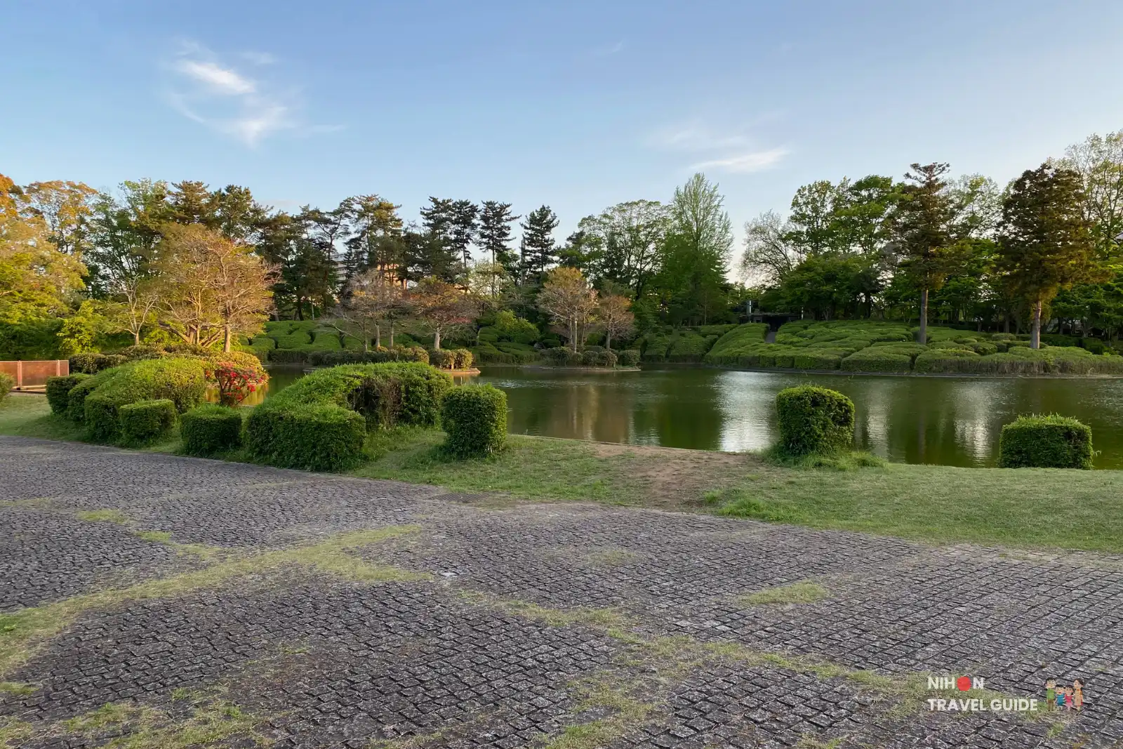 Beautiful pond surrounded by neatly trimmed bushes and trees at Matsumi Park in Tsukuba.