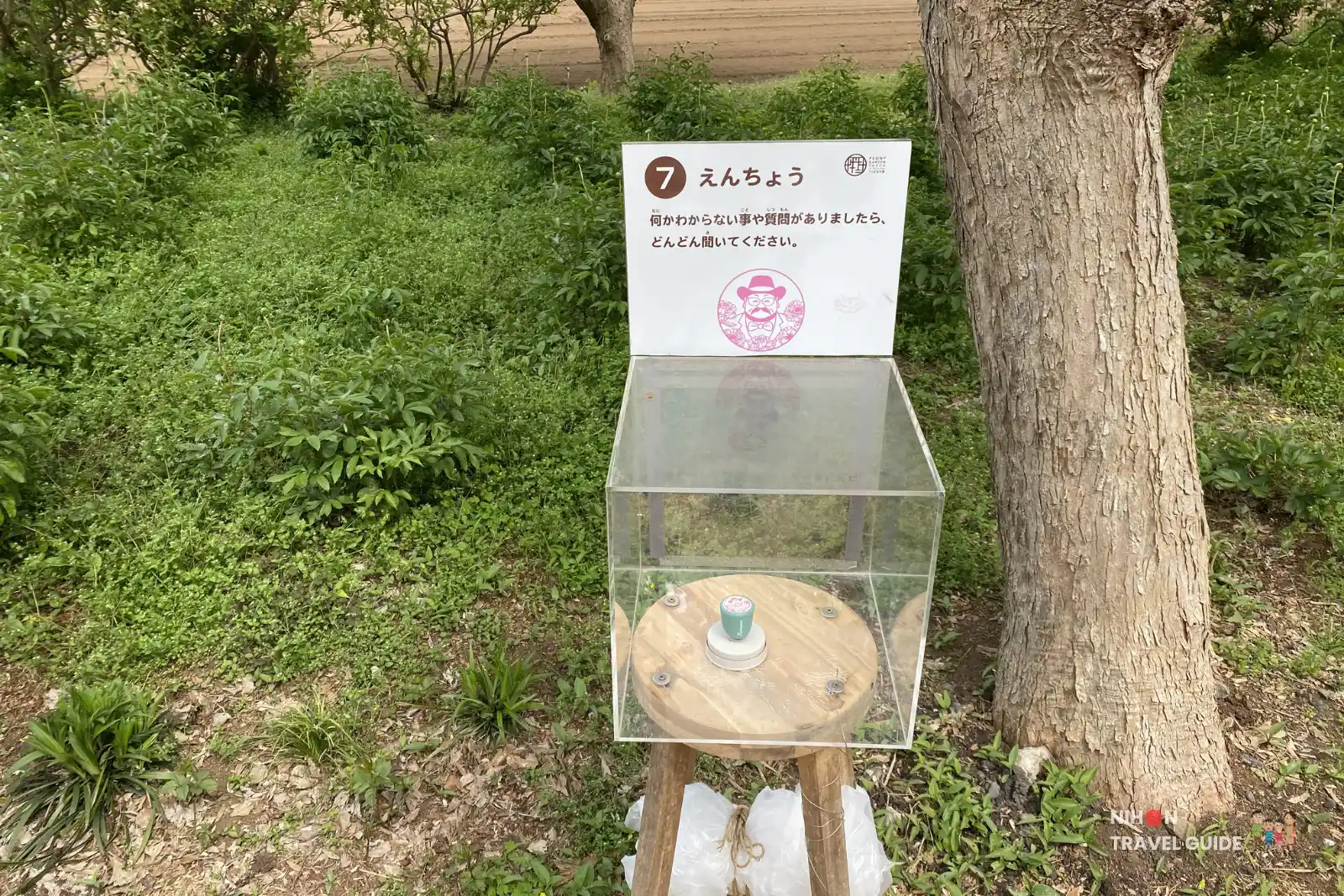 Stamp rally station No.7 "Enchō" (Garden Director/Staff) at Peony Garden Tokyo, inviting visitors to ask questions, with a cartoon illustration of the garden director.