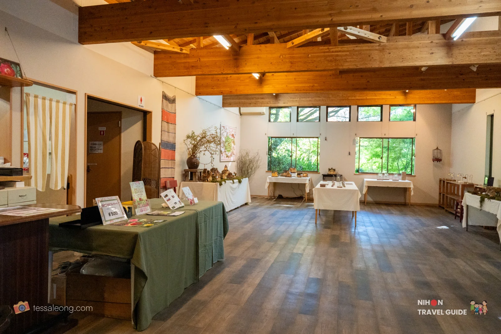 peony-garden-tokyo-harvest-cafe-gallery-interior Spacious interior of the Harvest Cafe and Gallery shop at Peony Garden Tokyo, featuring wooden ceiling beams, display tables with souvenirs and merchandise, and large windows overlooking the lush green garden.