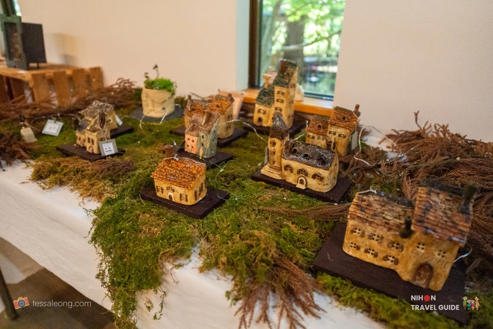 Handmade miniature ceramic fairy houses and village cottages for sale in the Harvest Cafe / Garden Shop at Peony Garden Tokyo, beautifully displayed on moss and wood bases.