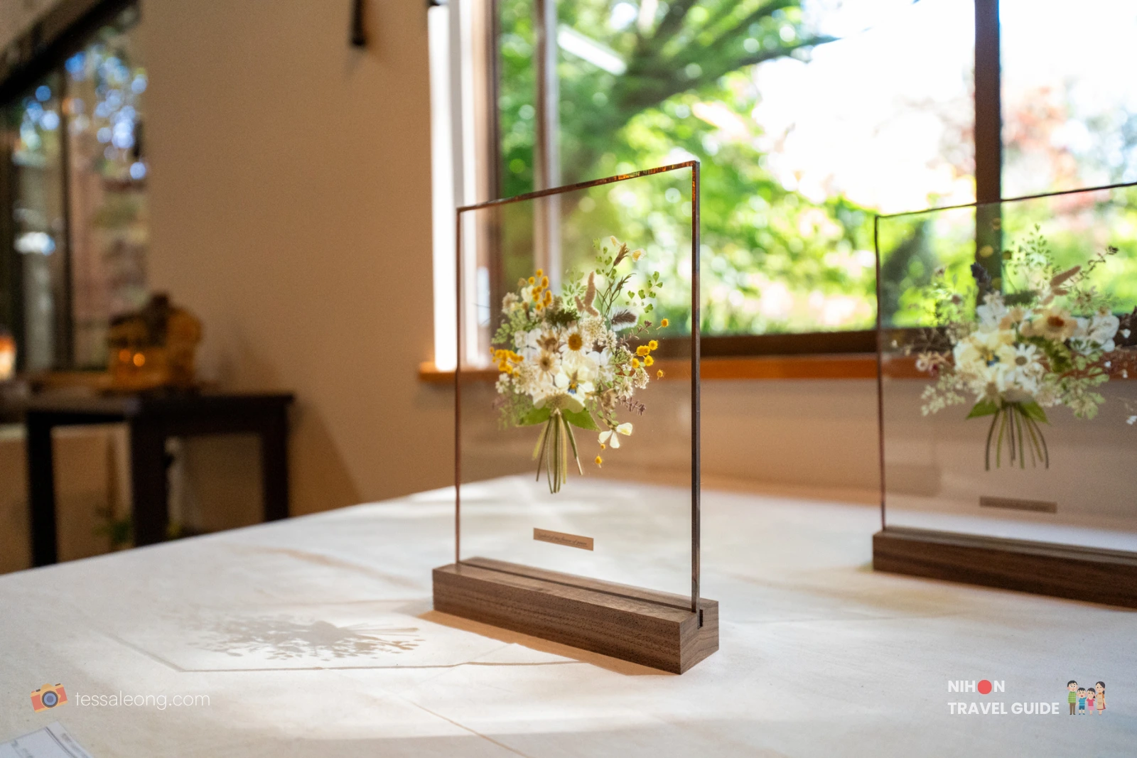 Elegant pressed flower artwork in glass frames displayed for sale inside the shop at Peony Garden Tokyo. Dried wildflowers and greenery preserved between glass with wooden bases.