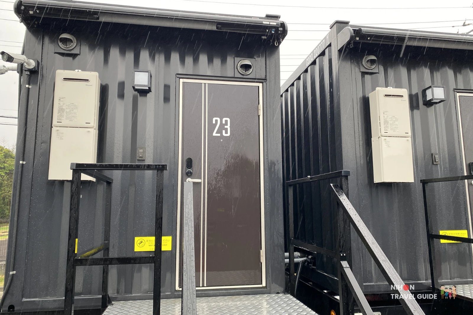 Exterior entrance of Room 23 at R9 The Yard Hotel Hitachinaka Ichige – black container-style room with stairs on a rainy day