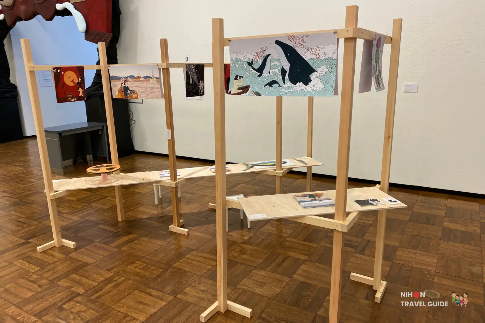 Tempest installation by Kuroda Sakuraumi — wooden modular display racks with large orca prints and narrative illustrations at the University of Tsukuba Master’s Degree Exhibition