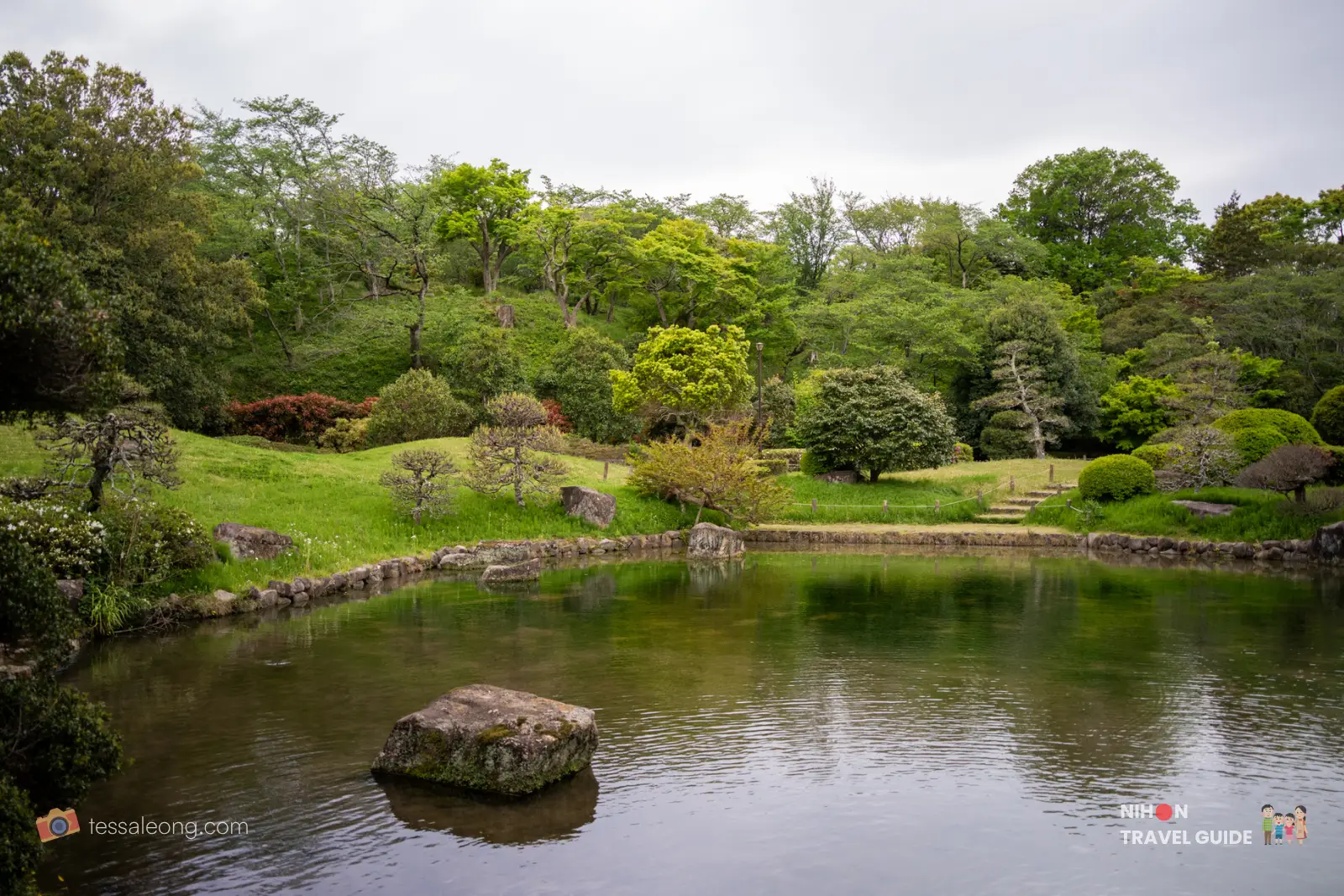 Calm pond surrounded by manicured hills and trees in the Japanese Garden at Akebonoyama Park