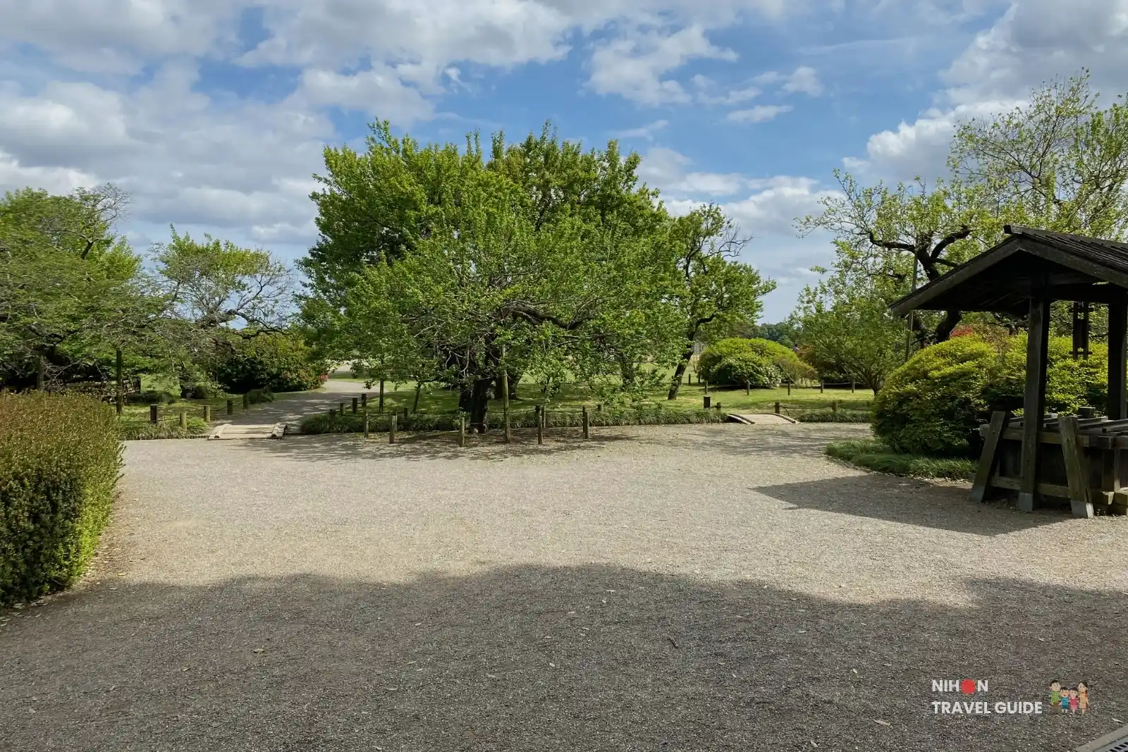 Open gravel plaza and spacious lawn area surrounded by trees at Kairakuen Garden in Mito.
