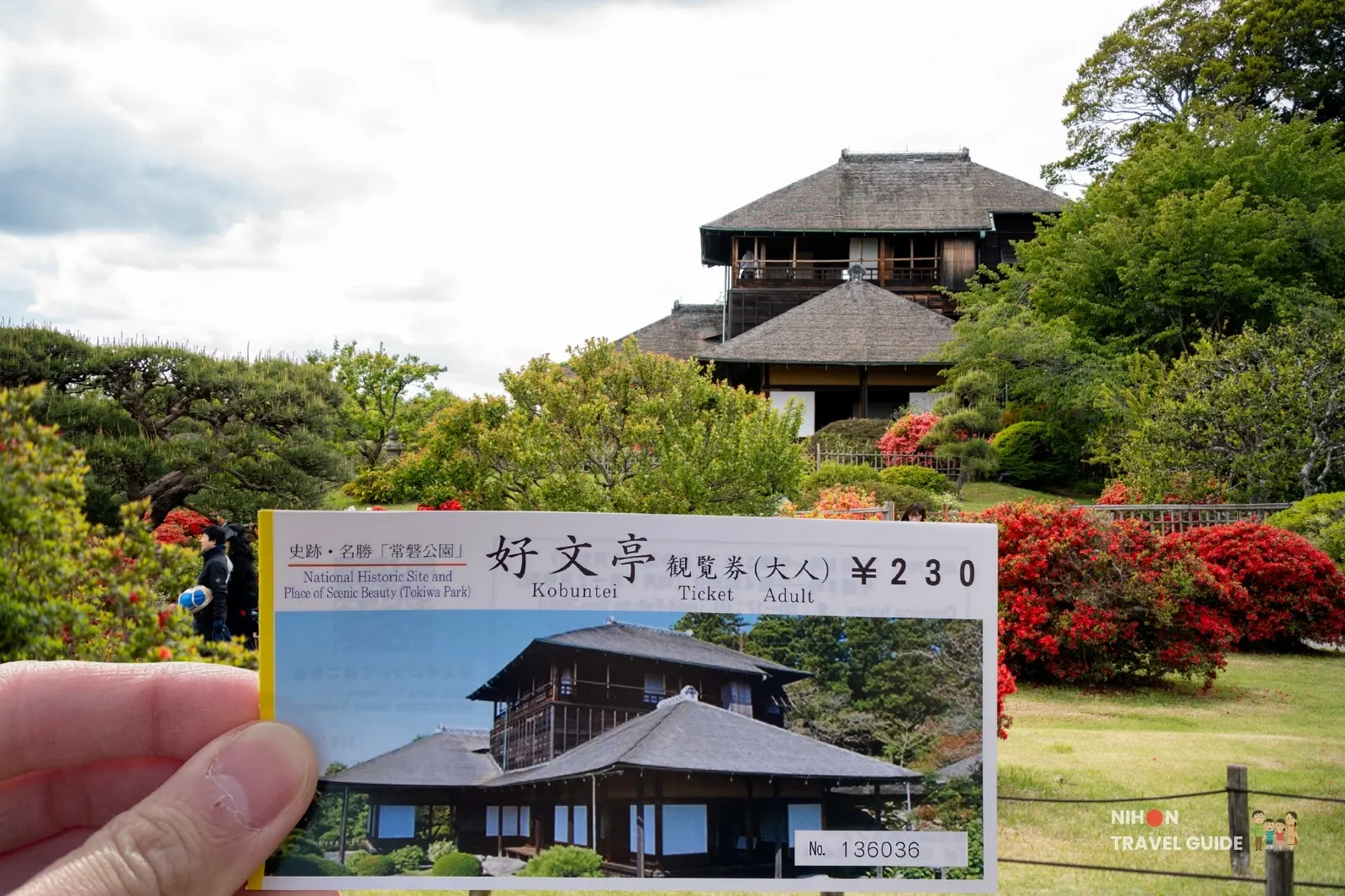 Hand holding a Kobuntei admission ticket in front of the historic three-story Kobuntei pavilion at Kairakuen Garden in Mito, with vibrant red azaleas in the foreground.