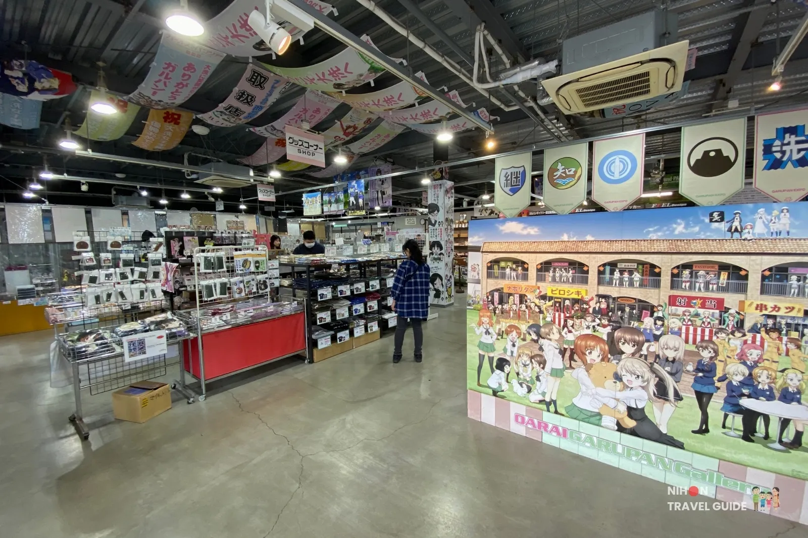 Wide view of Oarai Garupan Gallery shop floor with merchandise and large group poster.