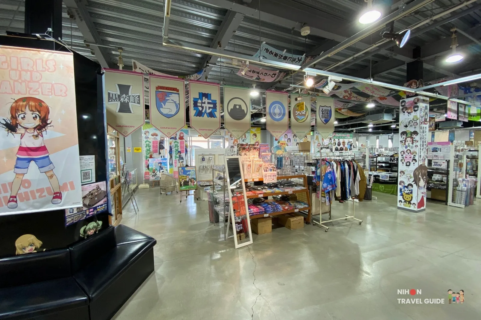 oarai-garupan-gallery-wide-interior-miho-poster-black-sofa Wide interior view of Oarai Garupan Gallery with Miho Nishizumi poster, black sofa, and school banners.