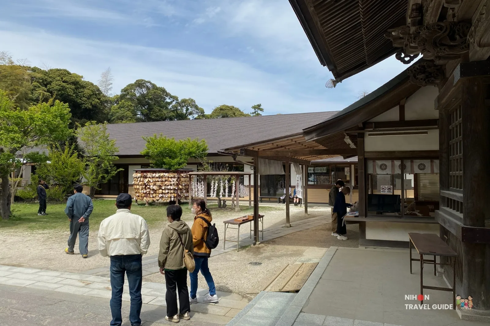 Visitors walking in the courtyard near the ema plaque rack and shrine buildings at Oarai Isosaki Shrine